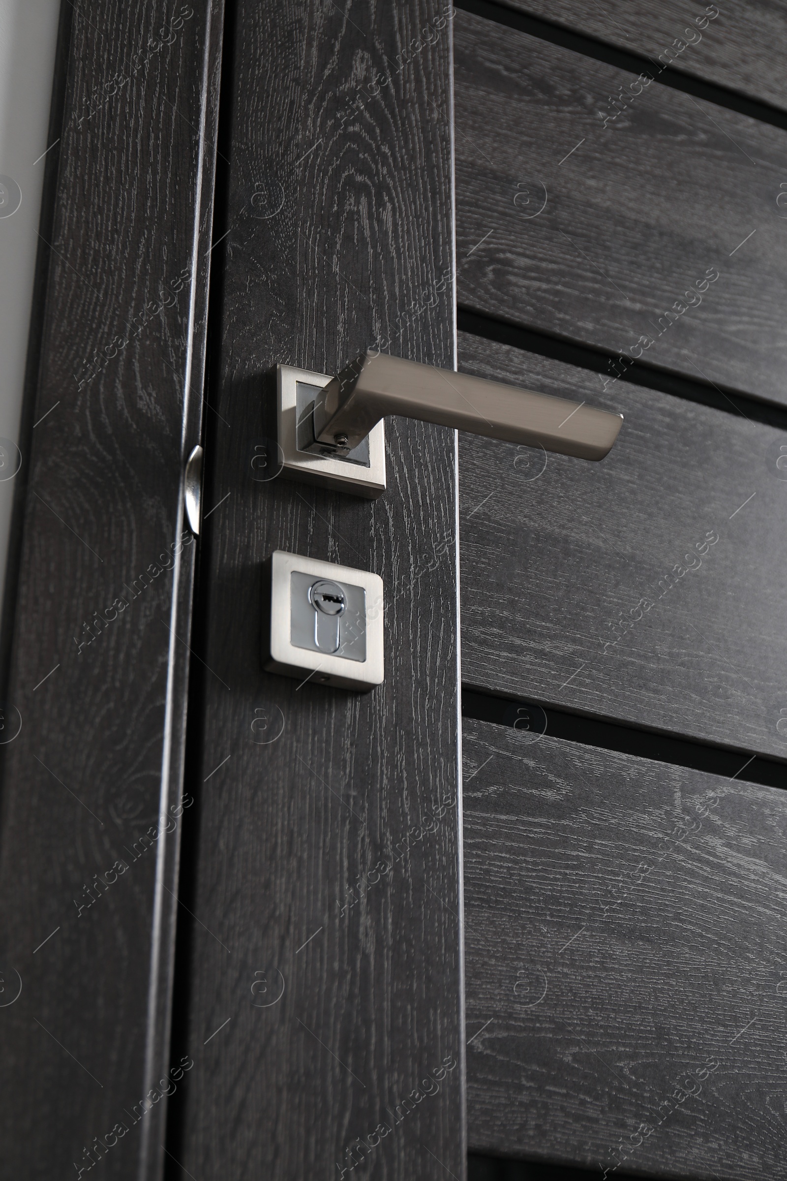 Photo of Dark wooden door with metal handle, low angle view