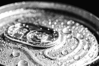 Photo of Aluminum can of beverage covered with water drops on black background, closeup