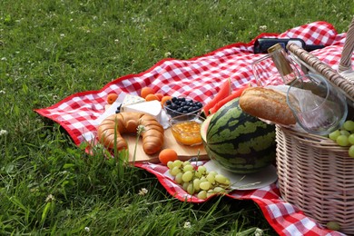 Photo of Picnic blanket with delicious food and wine outdoors on summer day