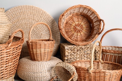 Photo of Many different wicker baskets made of natural material on light background, closeup