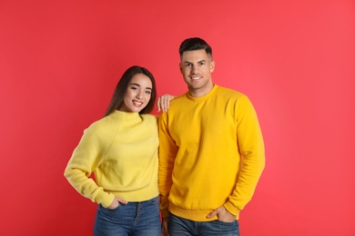 Happy couple wearing yellow warm sweaters on red background