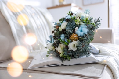 Photo of Beautiful wedding winter bouquet and book on sofa indoors, space for text. Bokeh effect