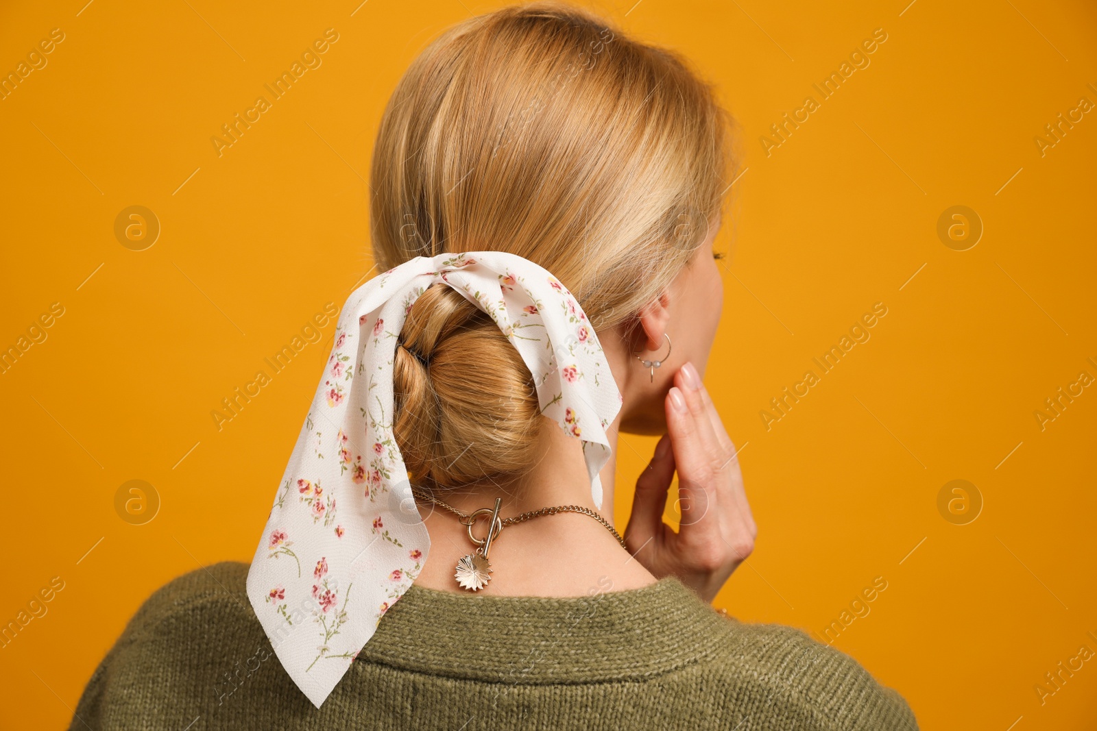 Photo of Young woman with stylish bandana on yellow background, back view