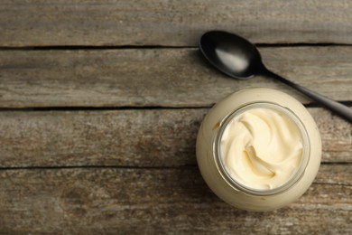 Photo of Jar of delicious mayonnaise and spoon on wooden table, flat lay. Space for text