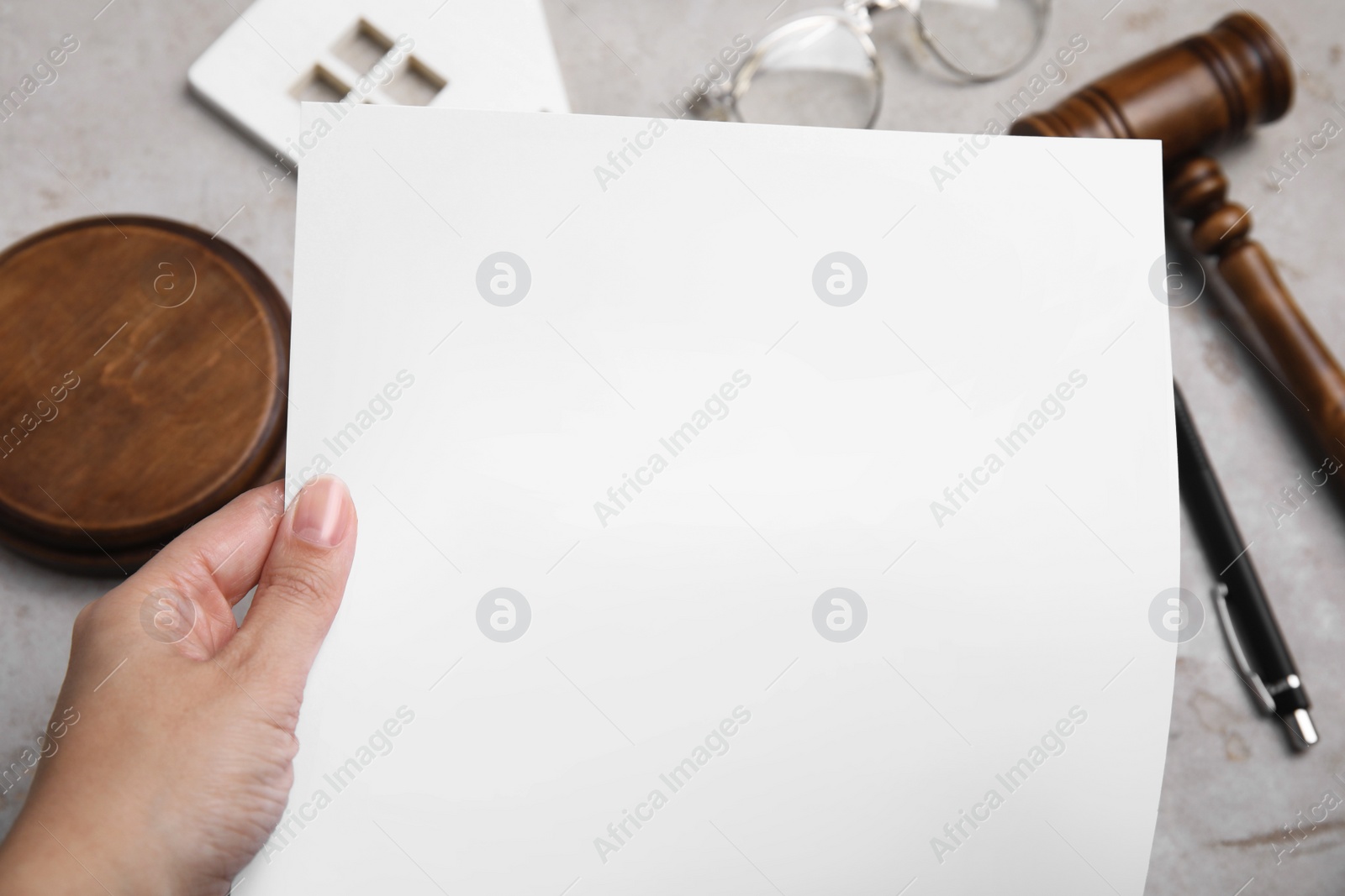 Photo of Woman holding last will and testament at light grey table, closeup