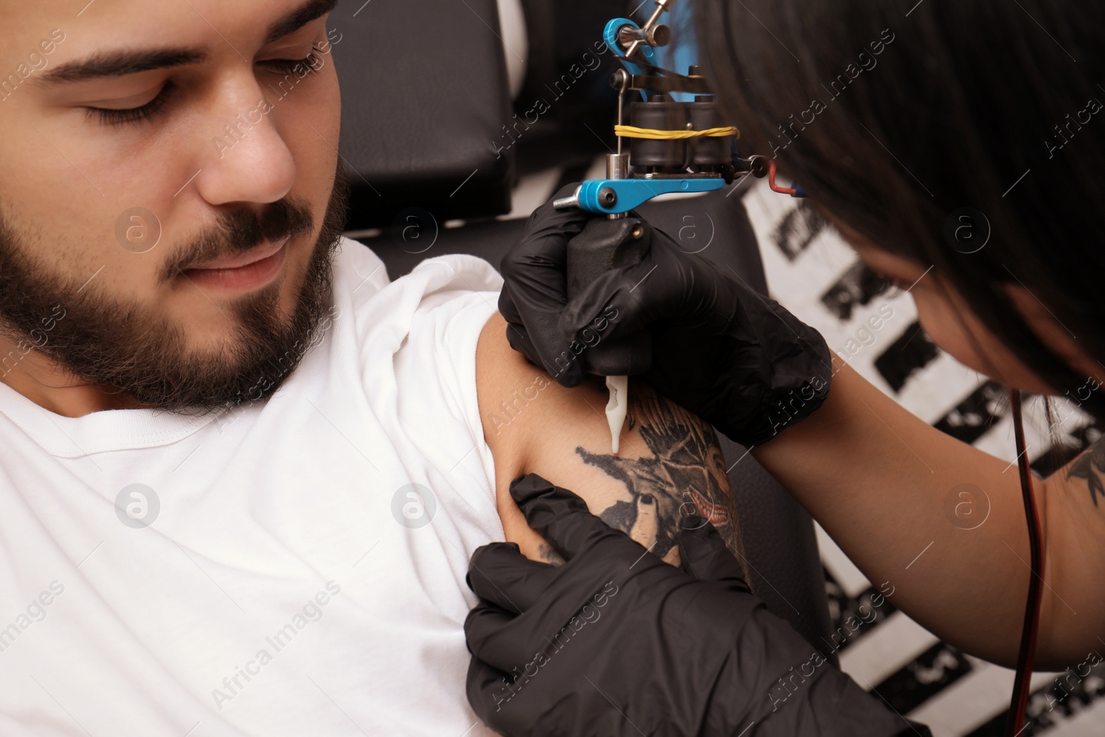 Photo of Professional artist making tattoo with machine in salon