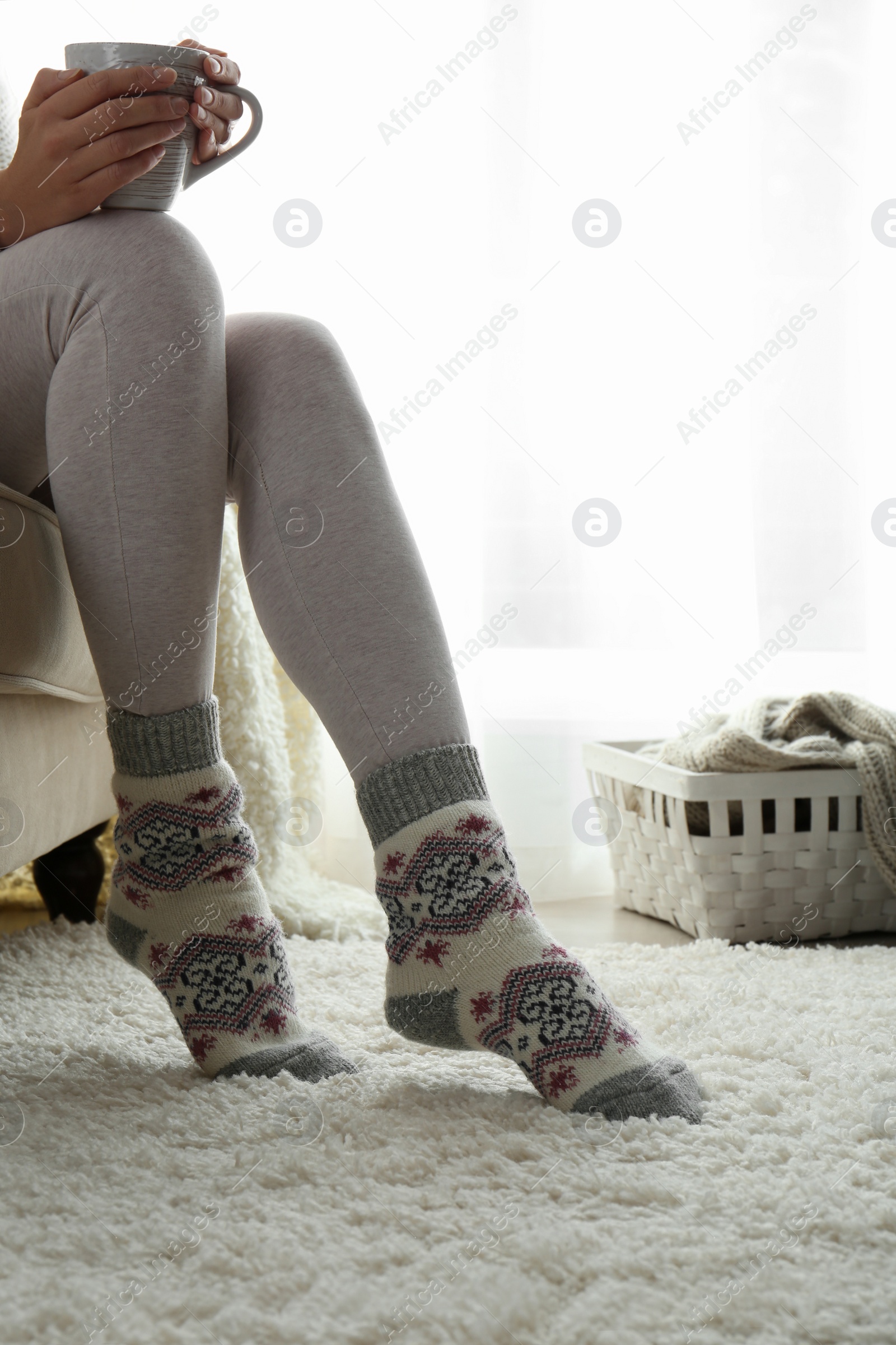 Photo of Woman wearing knitted socks at home, closeup. Warm clothes