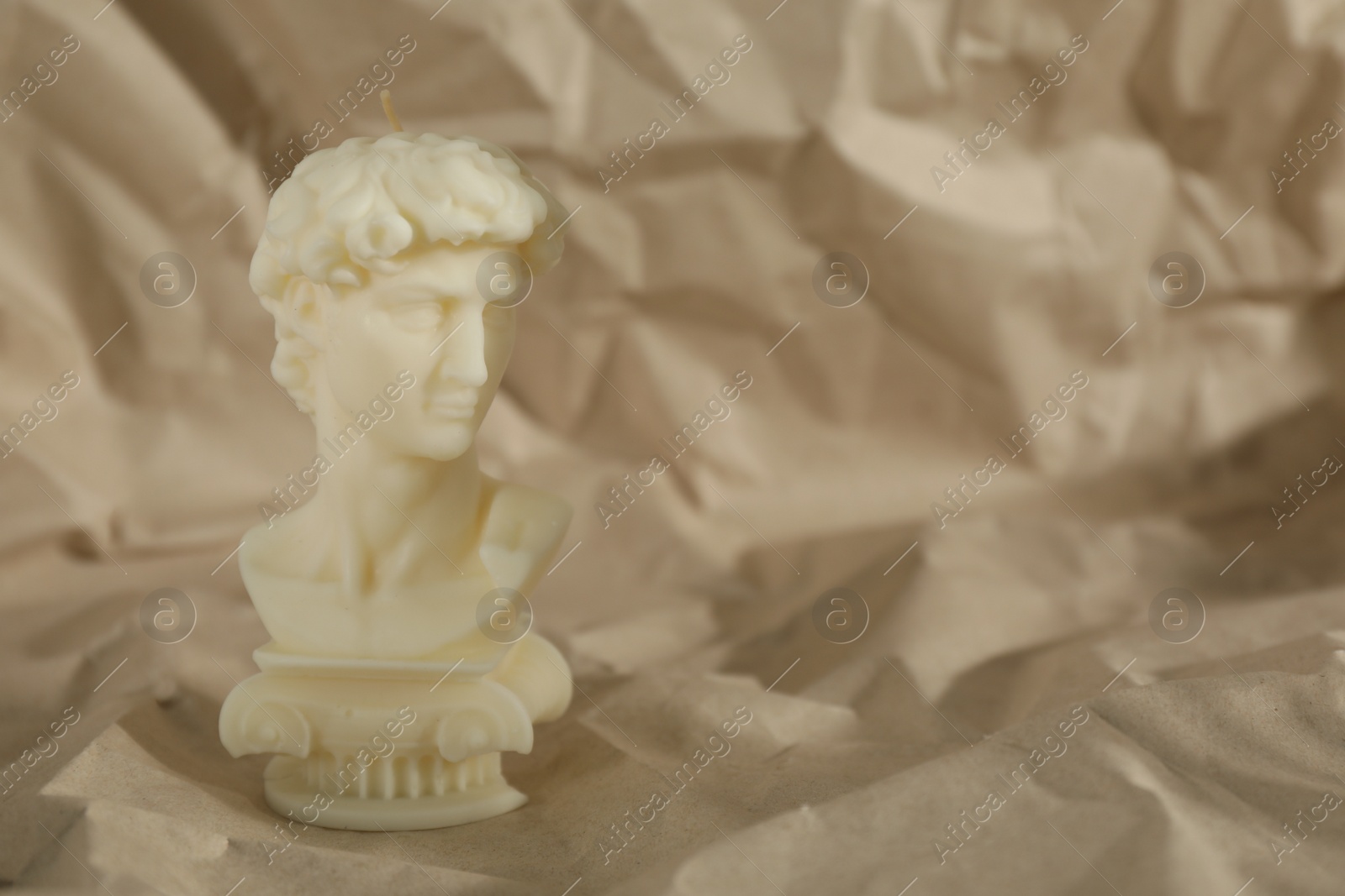 Photo of Beautiful David bust candle on crumpled paper. Space for text