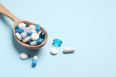 Photo of Many different pills and spoon on light blue background, space for text