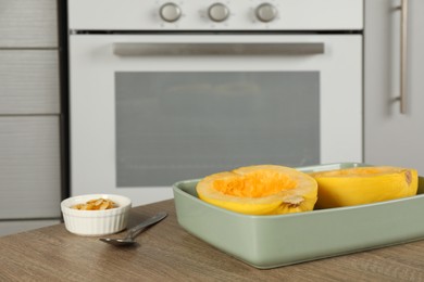 Photo of Halves of fresh spaghetti squash in baking dish on wooden table indoors, space for text