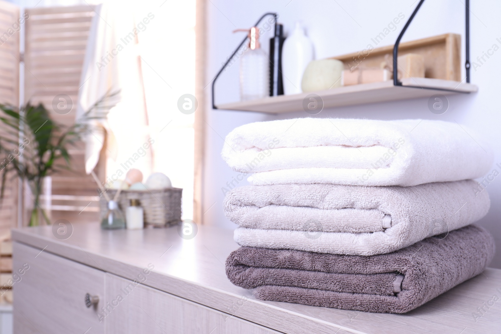 Photo of Stack of fresh towels on cabinet in bathroom. Space for text