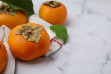 Delicious ripe juicy persimmons on white marble table. Space for text