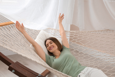 Photo of Happy woman lying in hammock at home