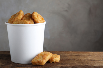 Bucket with delicious chicken nuggets on wooden table. Space for text