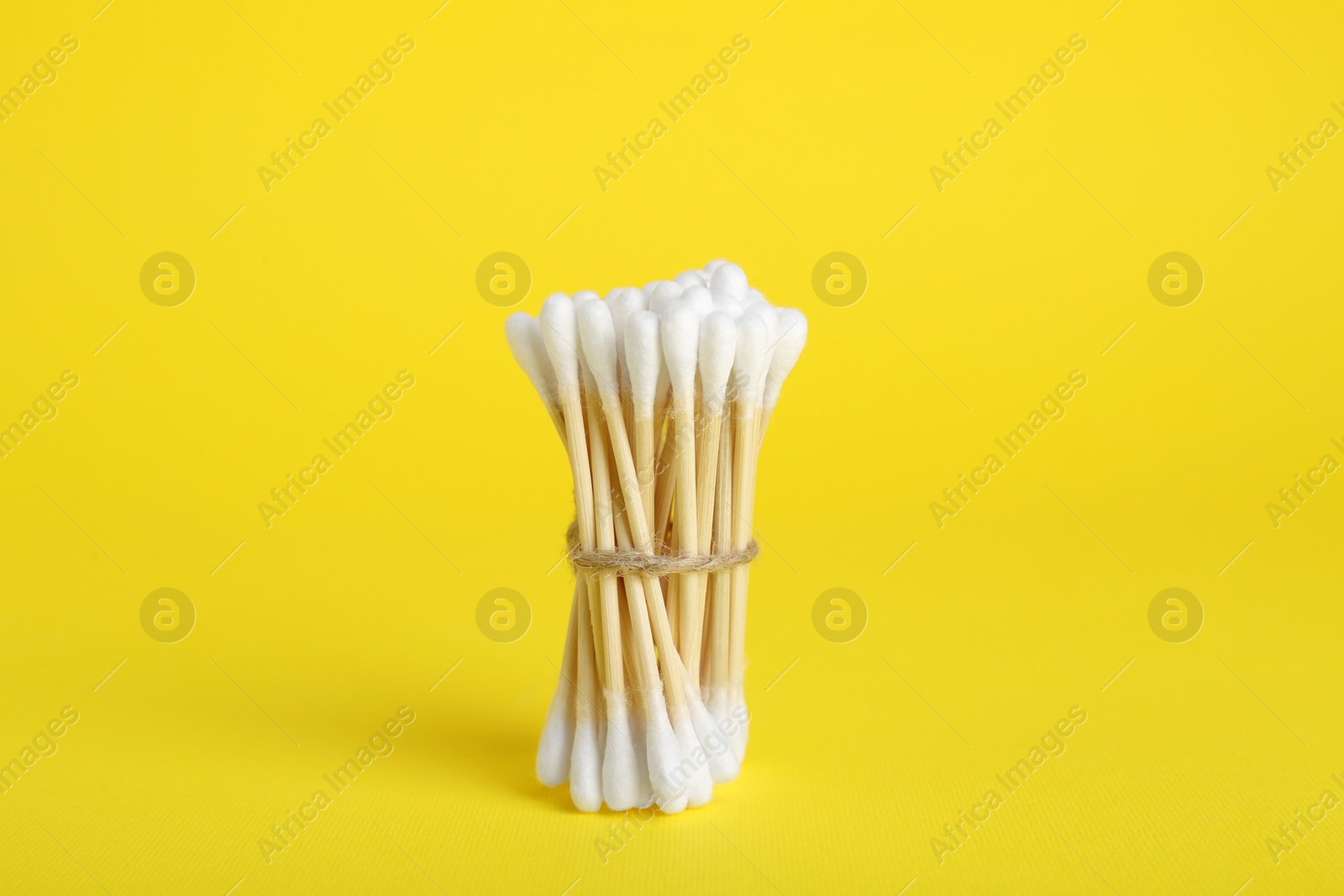 Photo of Bunch of new cotton buds on yellow background