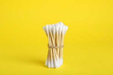 Photo of Bunch of new cotton buds on yellow background