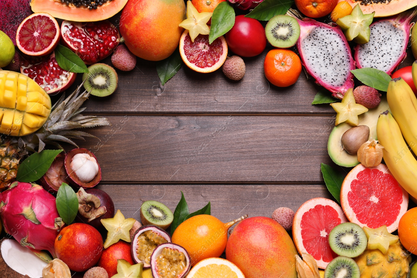 Photo of Frame of different exotic fruits on wooden background, flat lay. Space for text