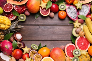 Photo of Frame of different exotic fruits on wooden background, flat lay. Space for text