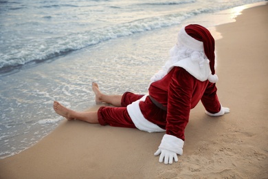 Photo of Santa Claus relaxing on beach. Christmas vacation