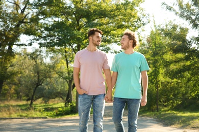 Happy gay couple walking in green park