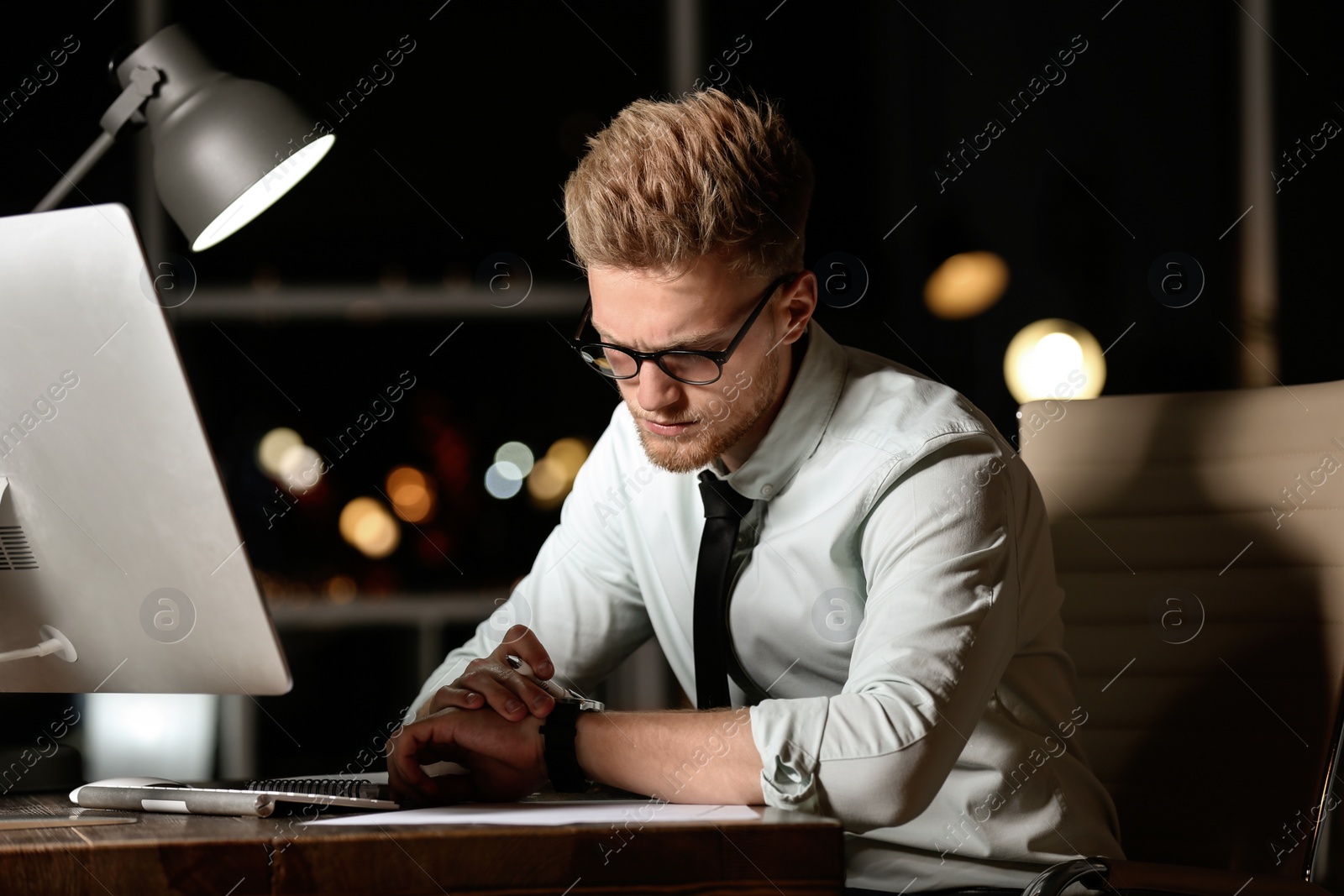 Photo of Young man working in office at night