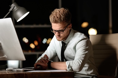 Photo of Young man working in office at night