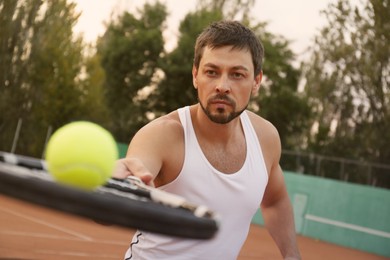 Handsome man playing tennis on court outdoors