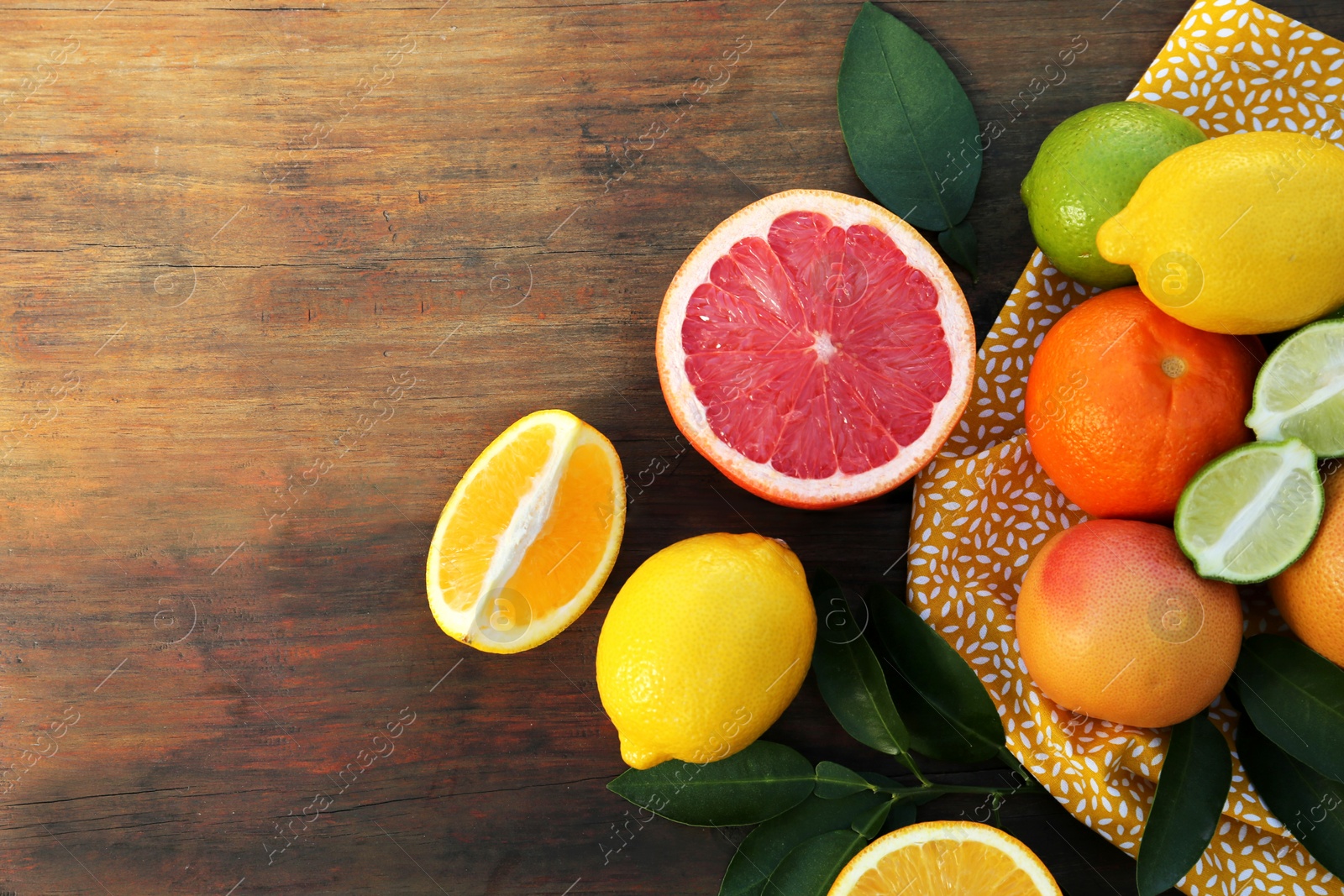 Photo of Different citrus fruits and leaves on wooden table, flat lay. Space for text