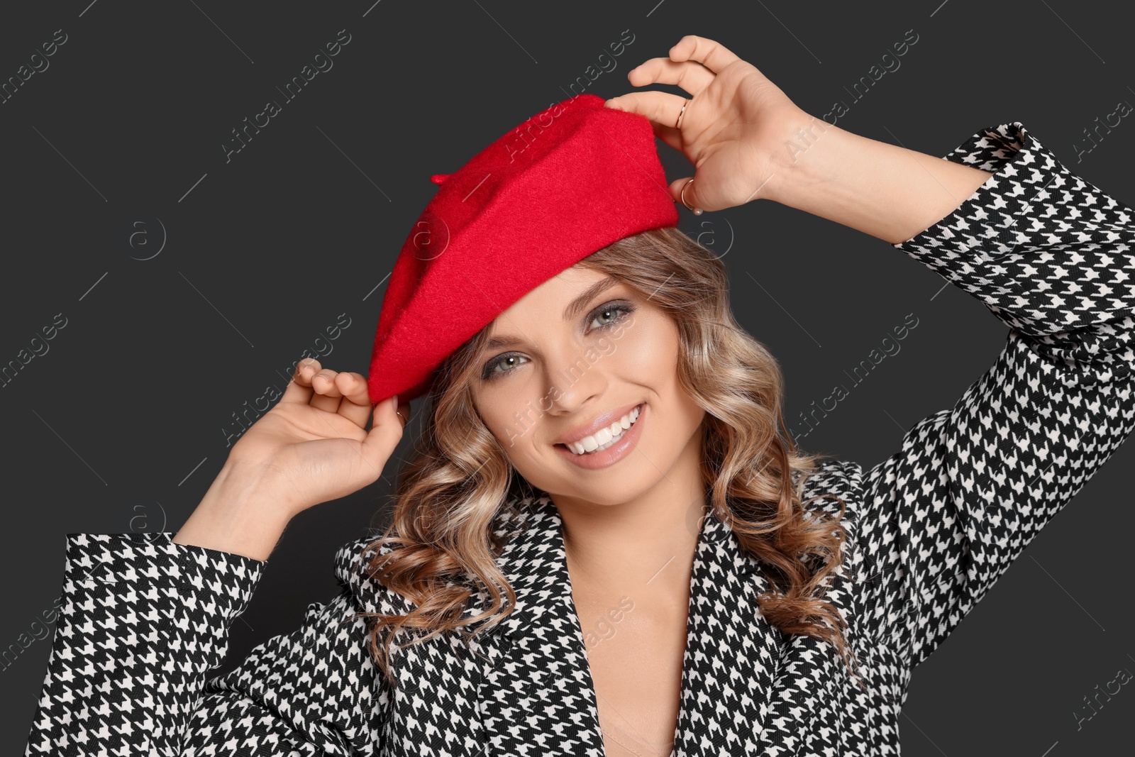 Photo of Young woman with beautiful makeup in red beret against black background