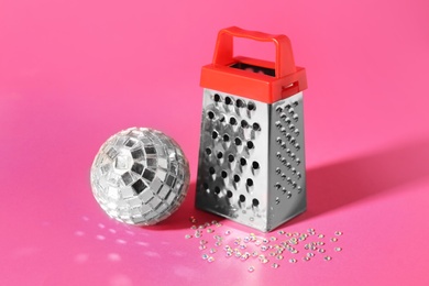 Photo of Grater and silver disco party ball on pink background