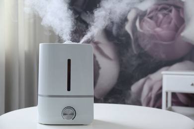 Photo of Modern air humidifier on table indoors. Space for text