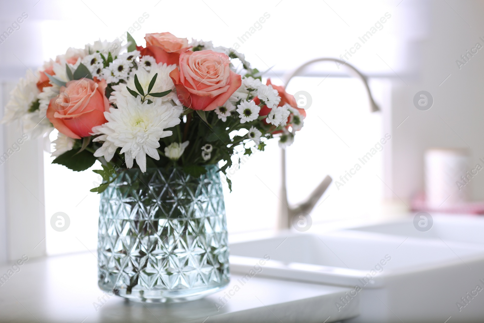 Photo of Vase with beautiful flowers on countertop in kitchen, space for text. Interior design