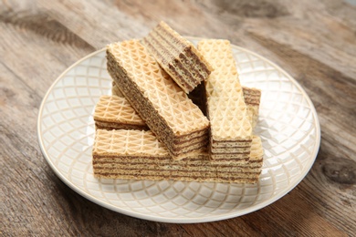 Photo of Plate of delicious wafers on brown wooden background