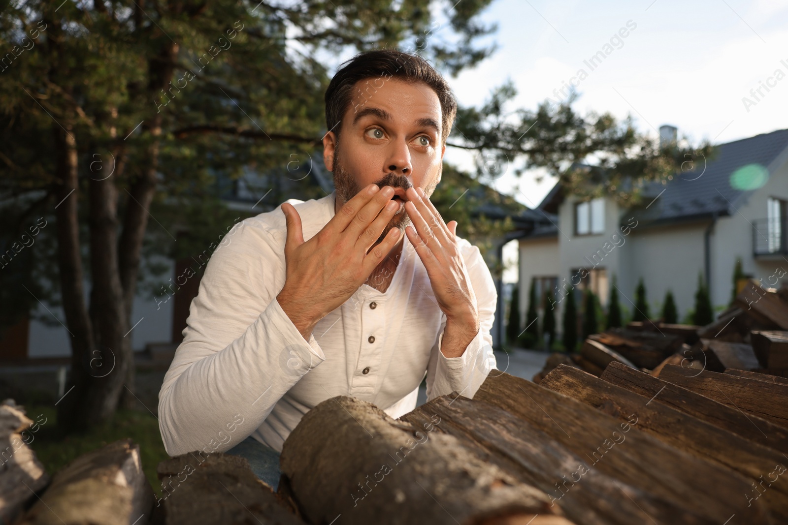 Photo of Concept of private life. Curious man spying on neighbours over firewood outdoors
