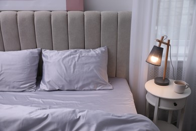 Photo of Cozy bed with soft silky bedclothes in light room