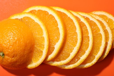 Slices of juicy orange on terracotta background, top view