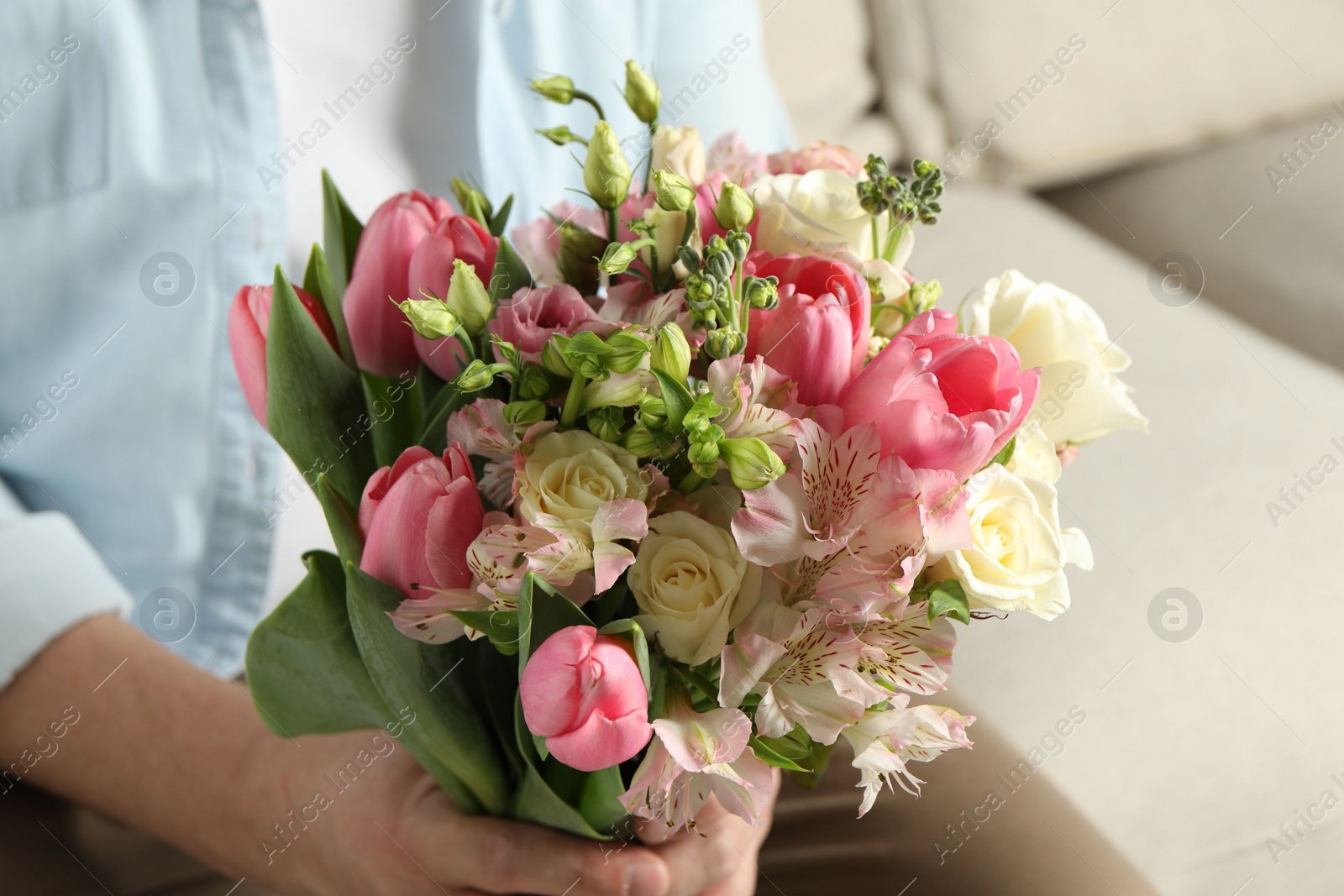 Photo of Man holding bouquet of beautiful flowers indoors, closeup