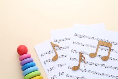 Photo of Wooden notes, music sheets and toys on beige background, flat lay with space for text. Baby song concept