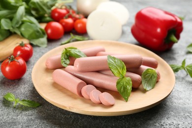 Photo of Fresh raw vegetarian sausages with basil and vegetables on grey table
