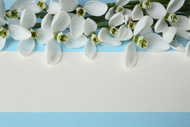 Photo of Beautiful snowdrops and paper card on light blue background, flat lay. Space for text