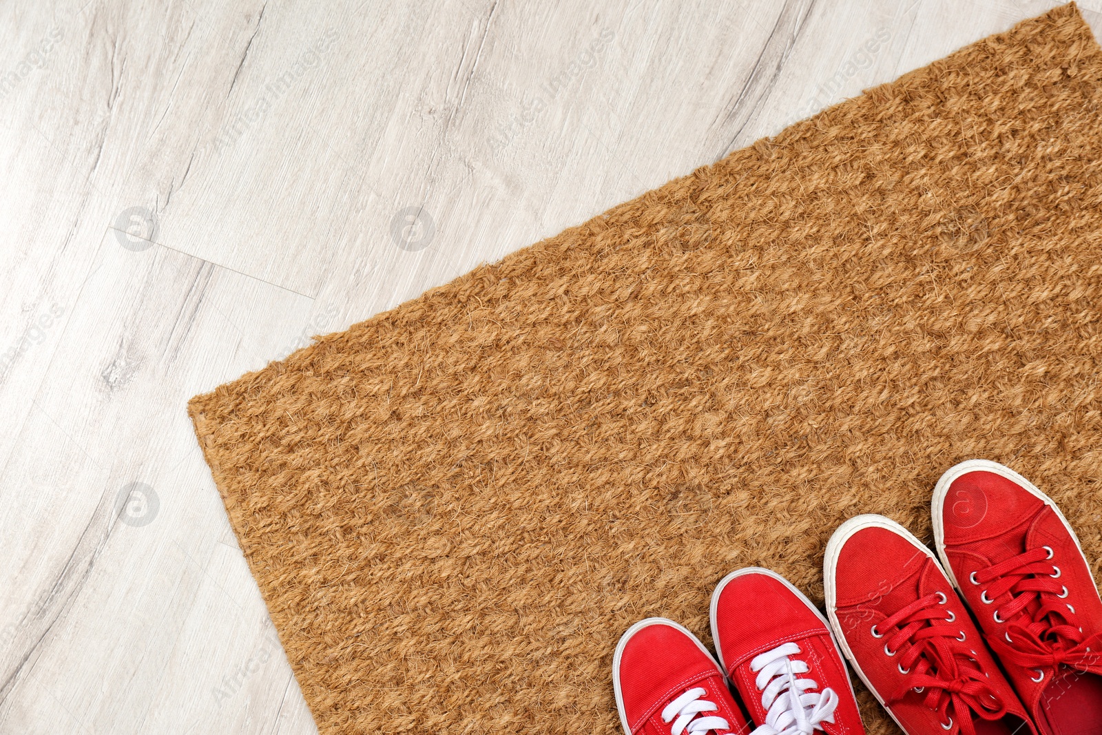 Photo of New clean doormat with shoes on floor, top view. Space for text