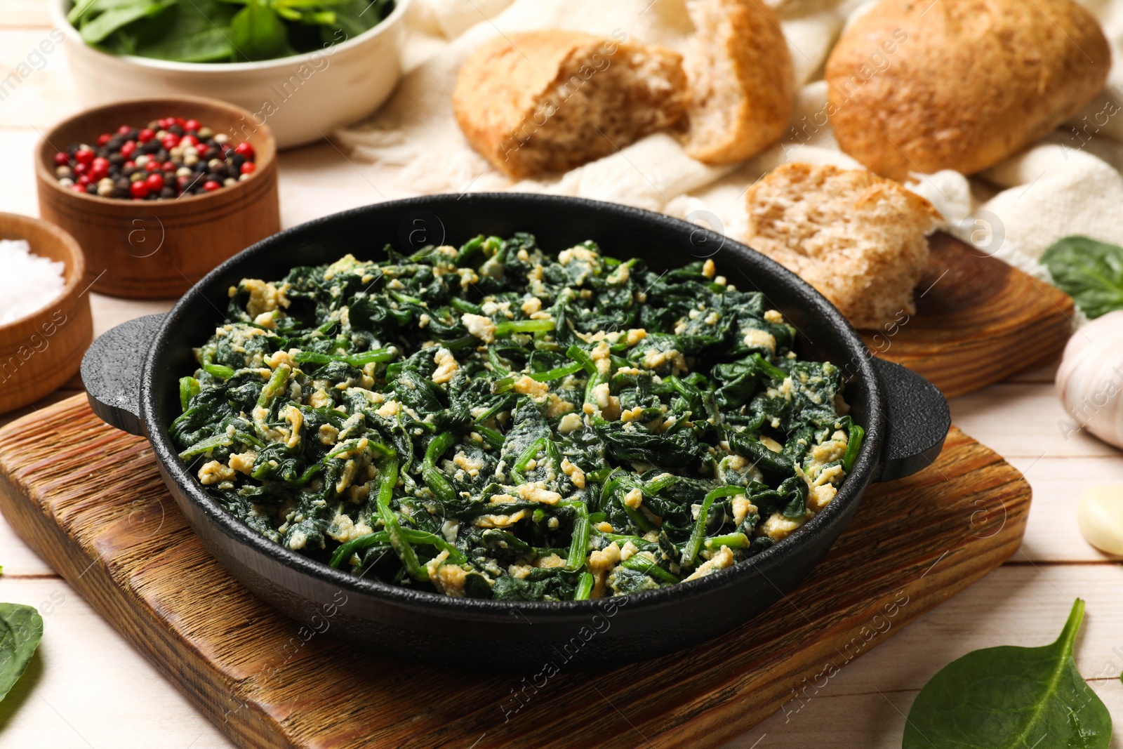 Photo of Tasty spinach dip with eggs in dish served on light wooden table, closeup