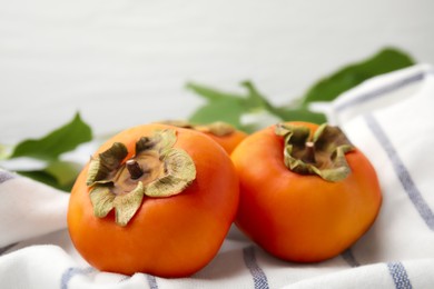 Photo of Delicious ripe juicy persimmons on striped cloth, closeup