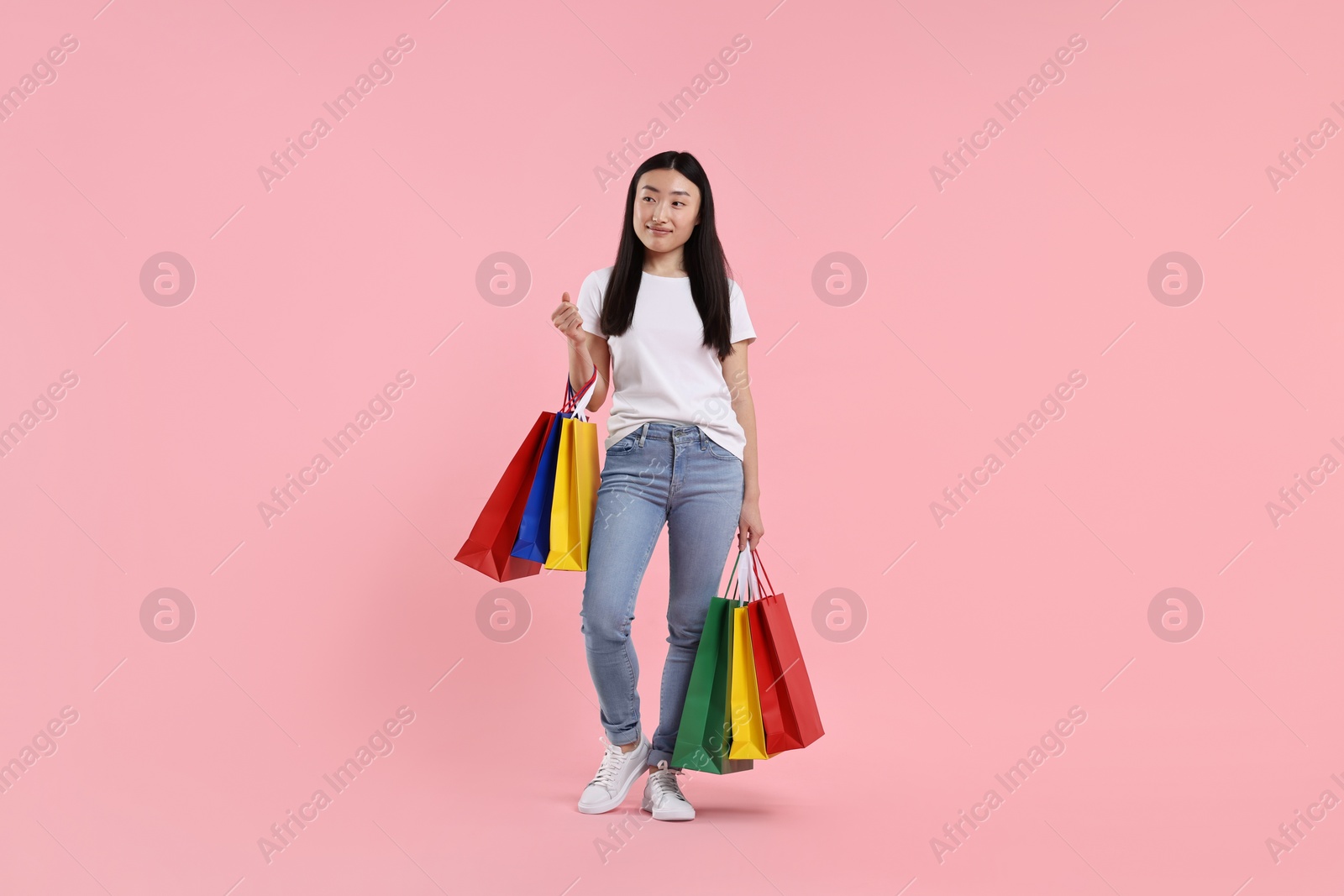 Photo of Beautiful woman with shopping bags on pink background