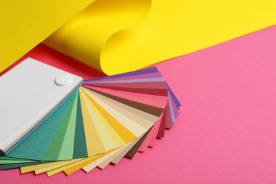 Photo of Color palette and yellow paper on pink background