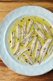 Tasty pickled anchovies with spices on wooden table, top view