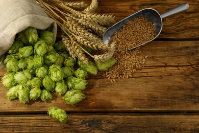 Fresh green hops, wheat grains and spikes on wooden table, flat lay