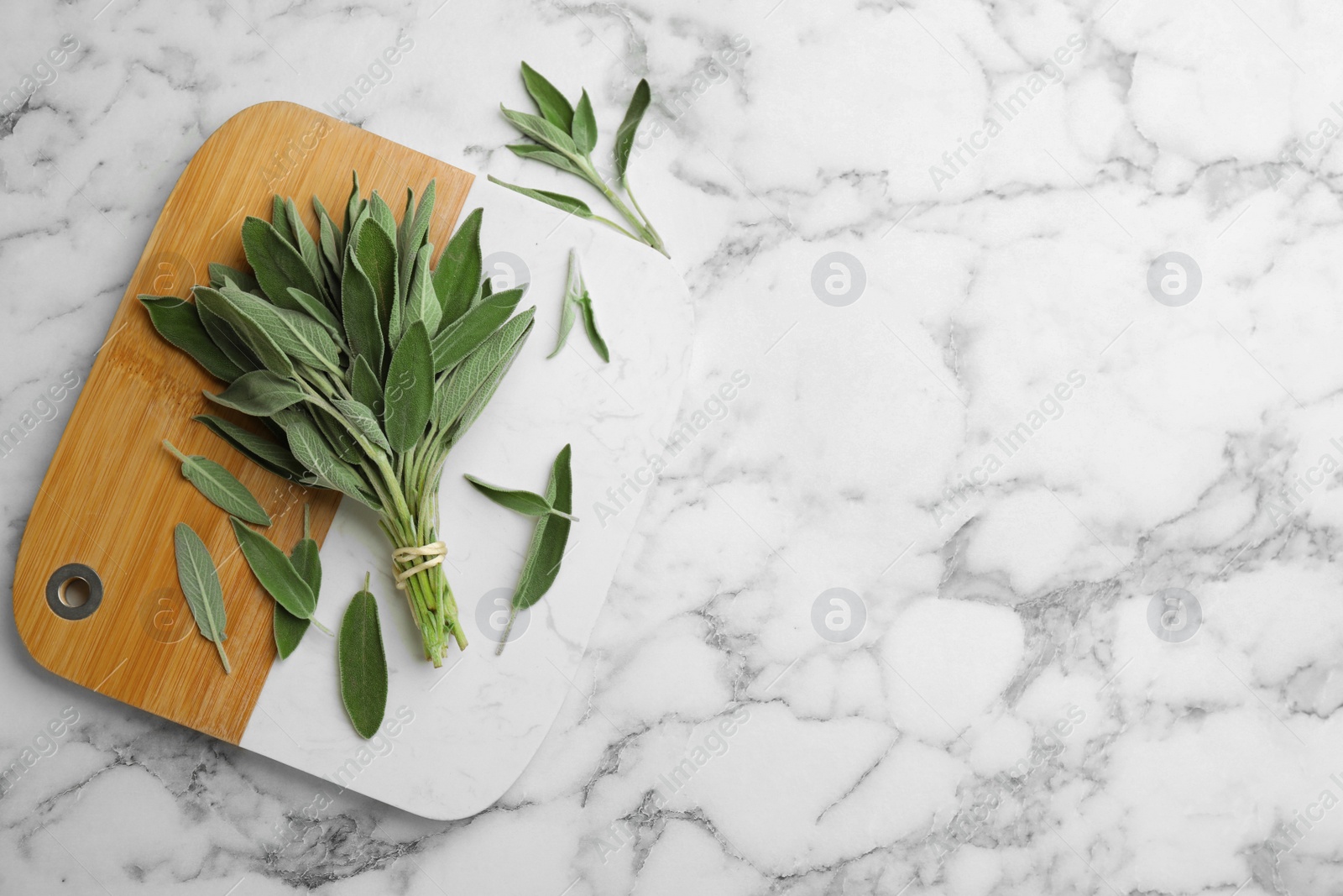 Photo of Board with fresh green sage on white marble table, flat lay. Space for text