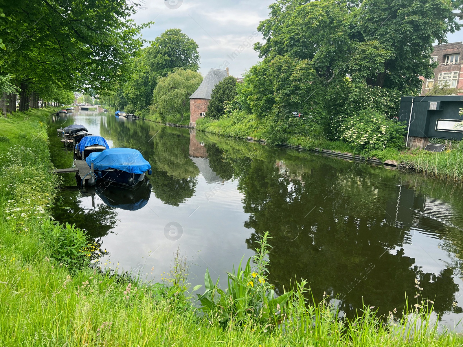 Photo of Beautiful view of city canal with moored boats surrounded by greenery