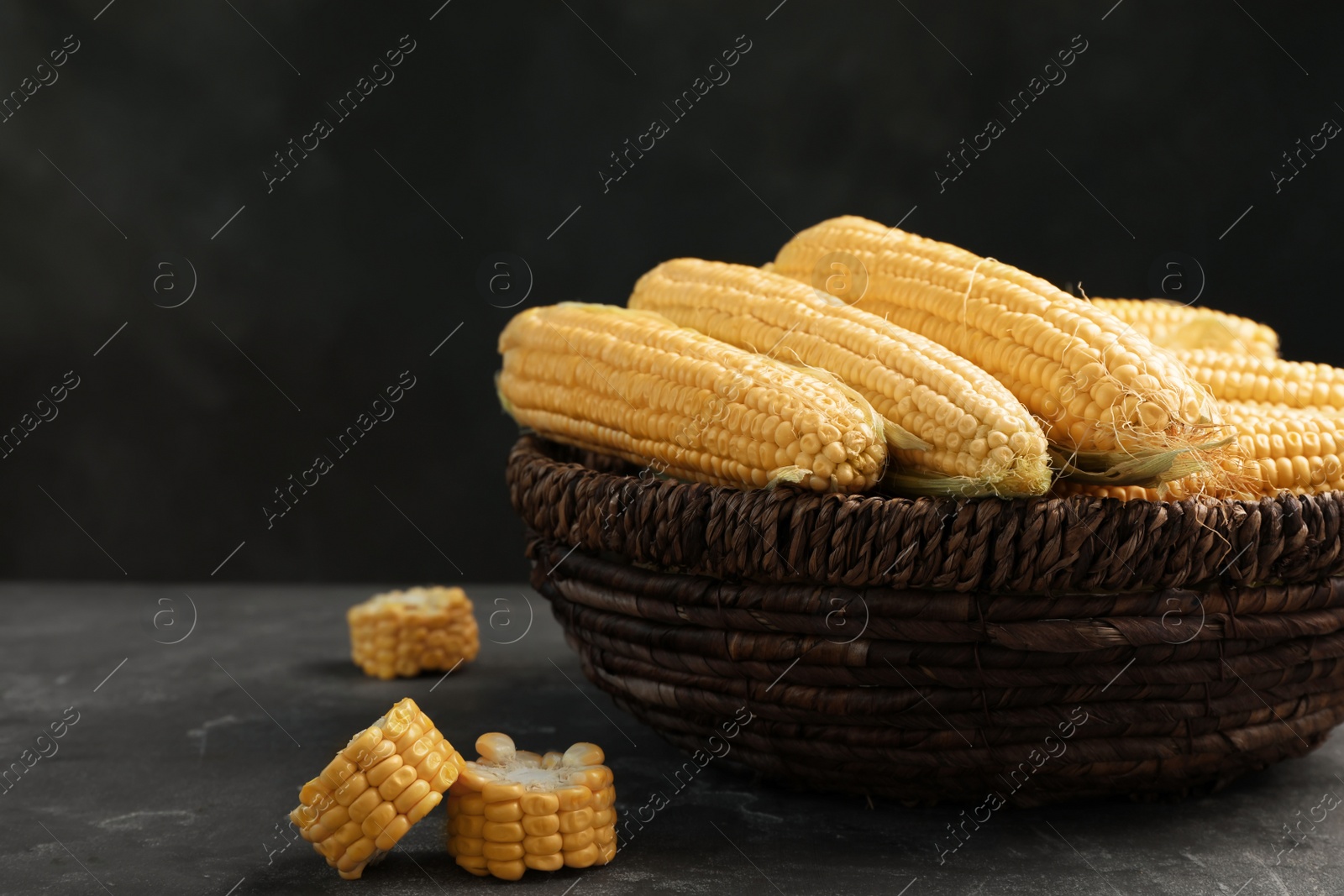 Photo of Basket with tasty sweet corn cobs on table